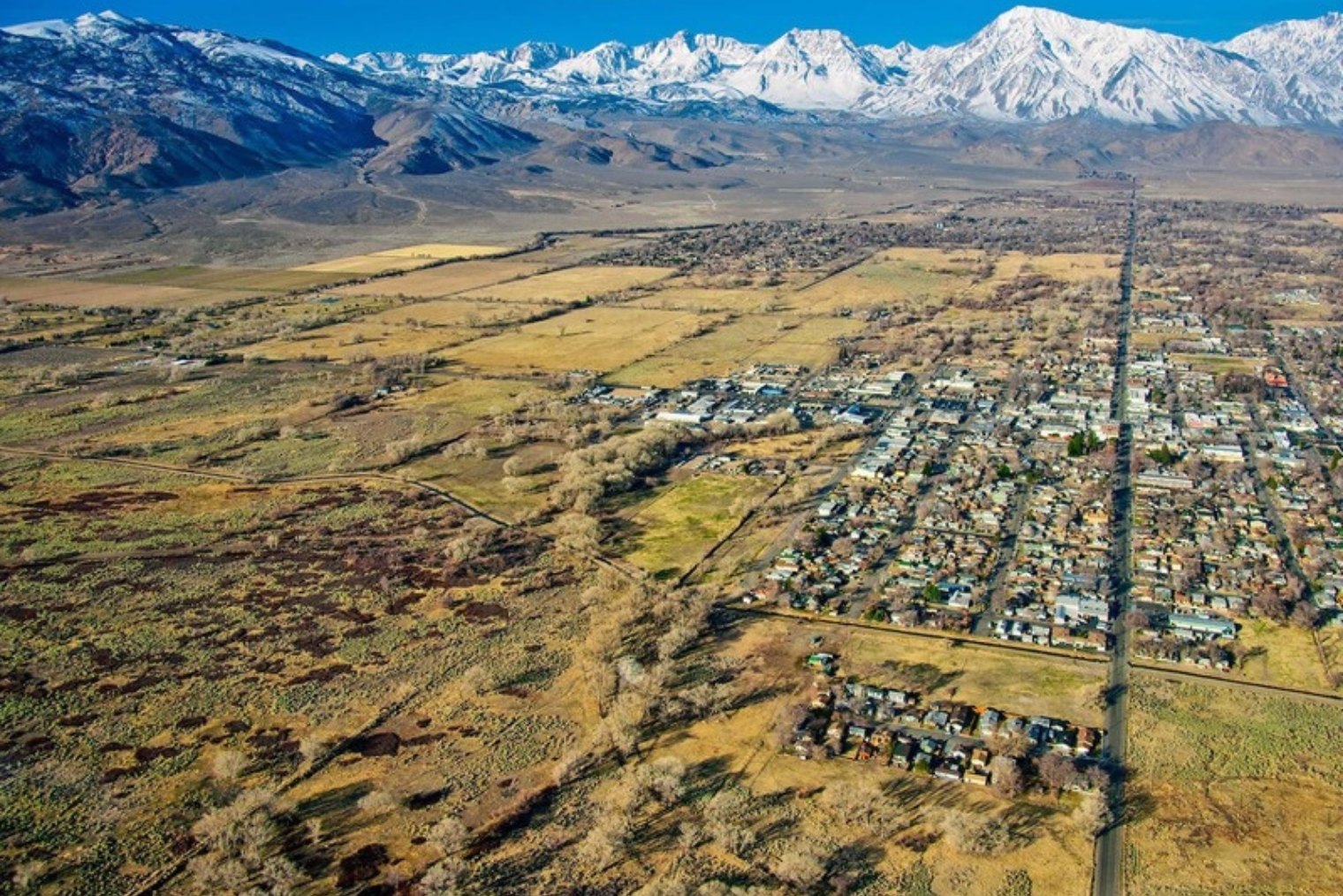 Aerial view of Bishop with green riparian corridors running through town toward the Sierra