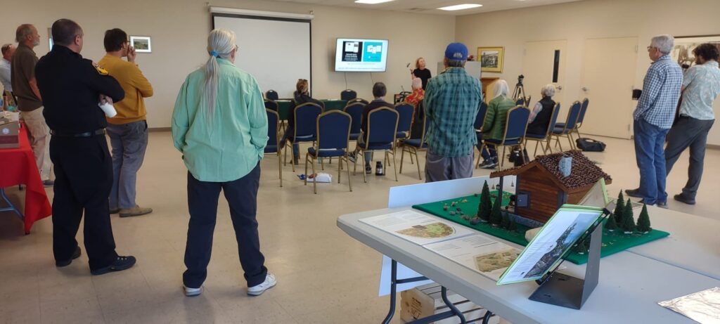 Residents gather for the community resilience presentation, with a model home defensible space display in the foreground